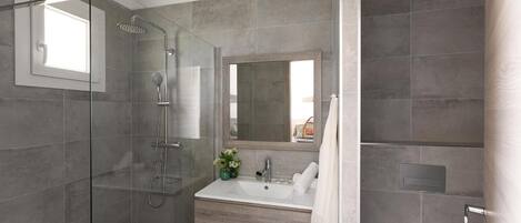 A modern bathroom with a glass-enclosed shower, a large mirror, and a vanity with a sink.