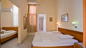Una habitación de hotel con dos camas individuales, un área de ducha y un pasillo que conduce a otra habitación.