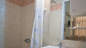Un baño con ducha, lavamanos y espejo.