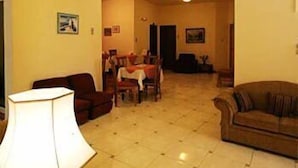 Una sala de estar con una lámpara, un sofá y un comedor al fondo.