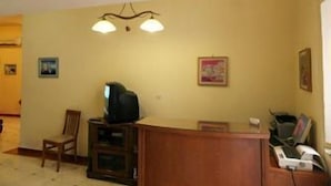 Una sala de estar con un escritorio de madera, televisor y una araña.
