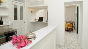 A modern kitchen with white cabinetry, a countertop with a decorative item, and a laptop on a shelf. - Il Ducato di Ravello (Ravello)