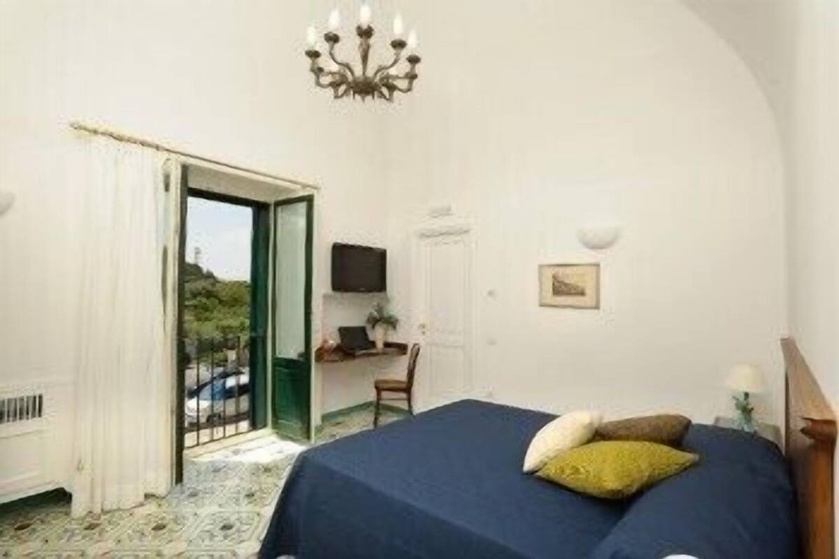 Un dormitorio con cama, escritorio, silla, televisor y candelabro.