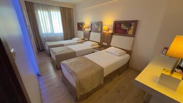 Camera d'albergo con due letti singoli, una scrivania, una sedia e una finestra con tende.