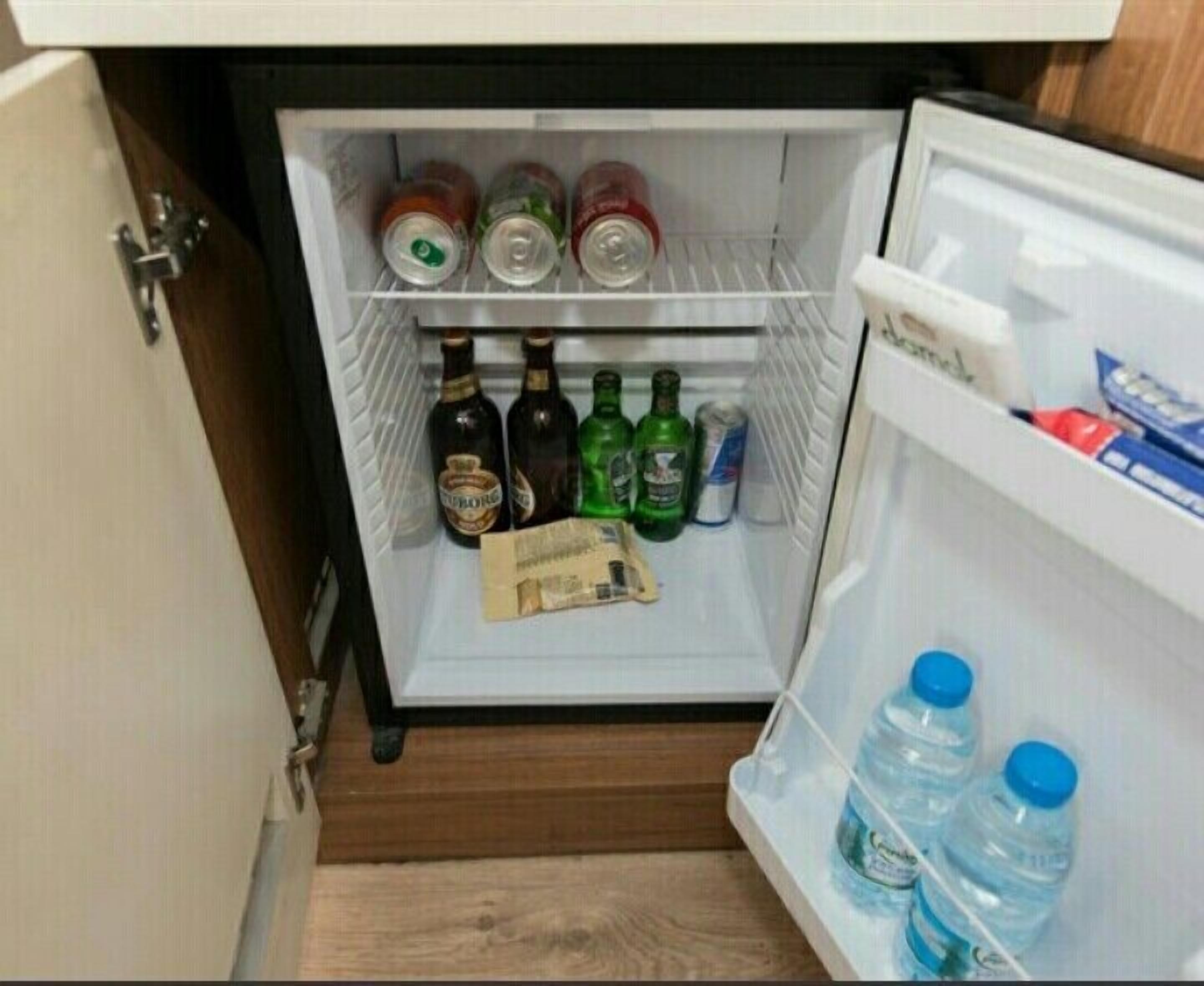 Un refrigerador con varias bebidas y una cajetilla de cigarrillos.