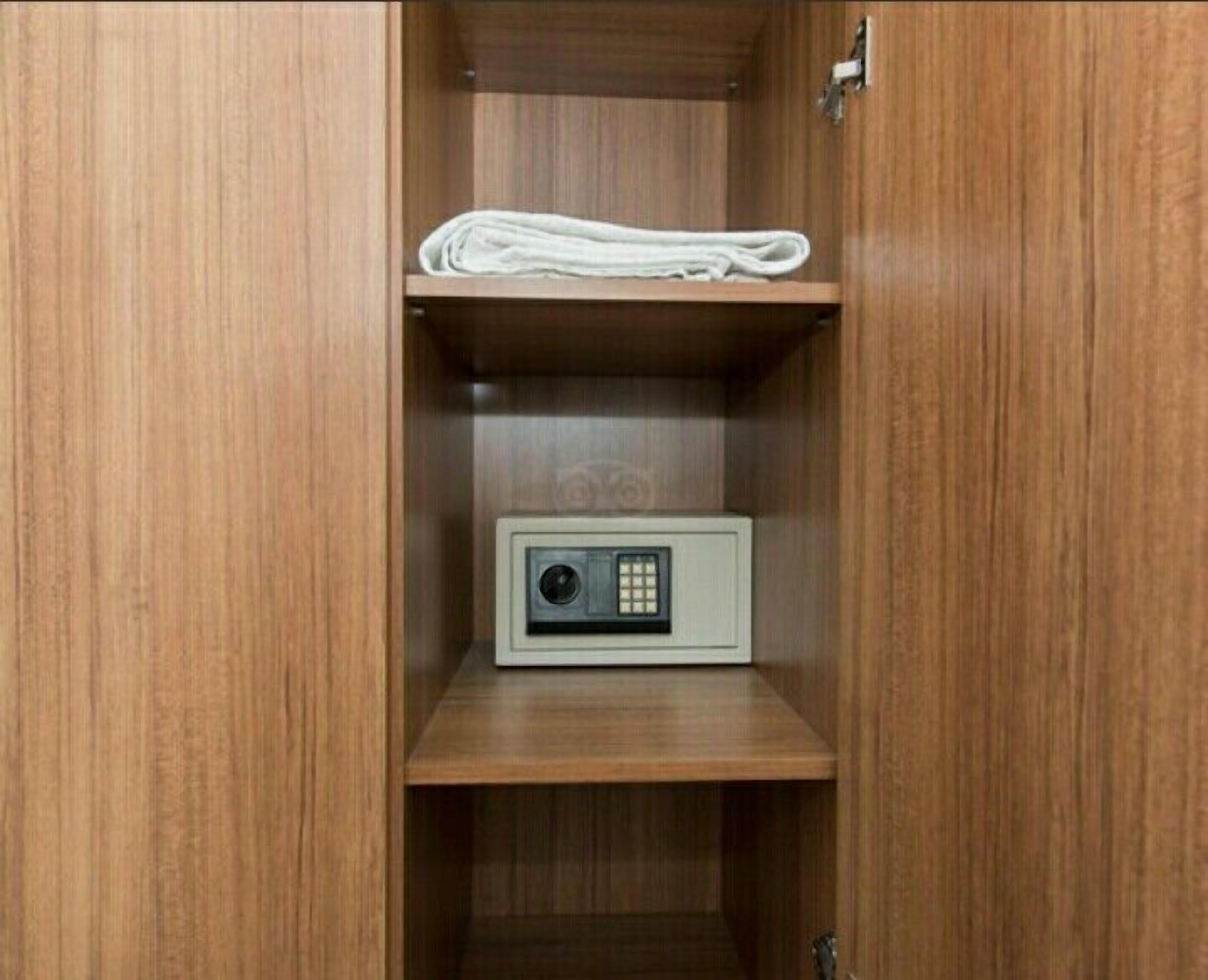 A wooden cabinet with a white towel on the top shelf and a small electronic device on the bottom shelf.