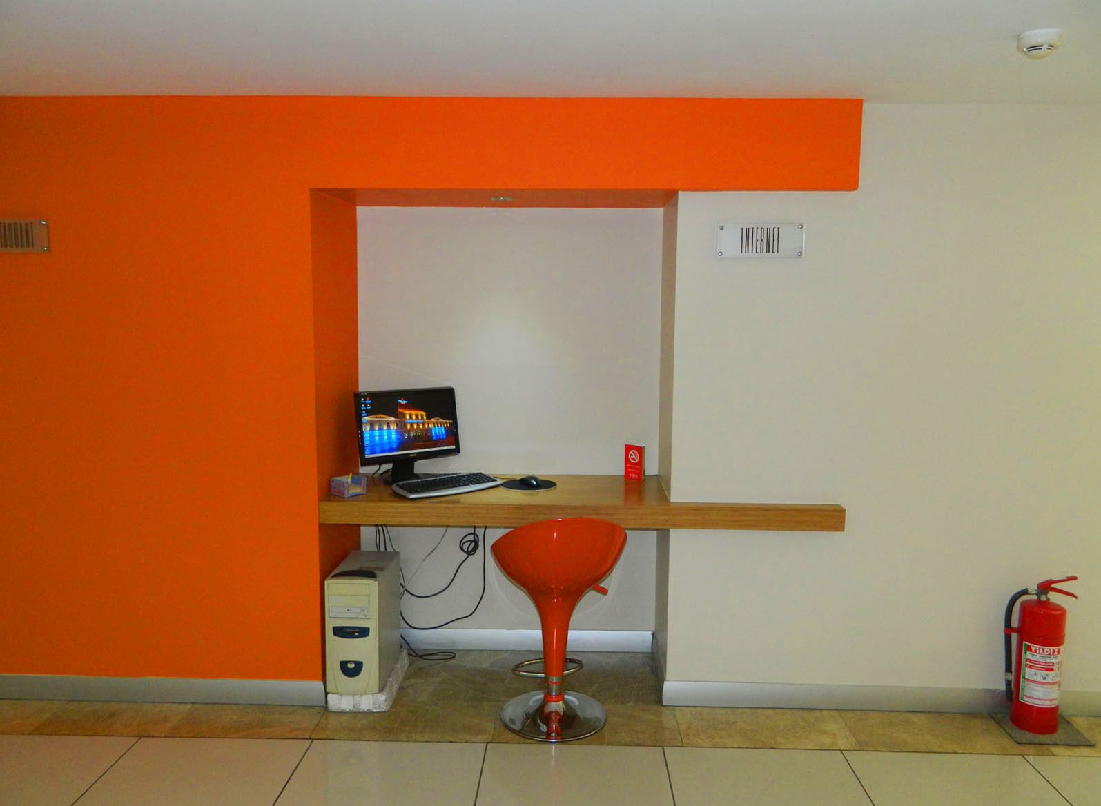 A small office space with a desk, computer, and chair, a fire extinguisher, and a sign labeled "INTERNET".