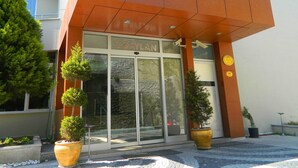 A modern hotel entrance with a glass facade, potted plants, and a sign reading "HOTEL BAYLAN". - Hotel Baylan Izmir (Izmir)