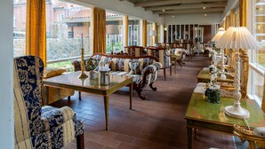 A spacious room with a long table, several upholstered chairs, and a green table with a lamp. - Sauntehus Slotshotel (Hornbaek)