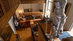 A high-ceilinged room with a wooden staircase, a bar area, and a large metal sculpture. - Sauntehus Slotshotel (Hornbaek)