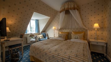 Un dormitorio con una cama grande, dos mesitas de noche con lámparas, una silla, un escritorio con computadora y una ventana con cortinas.
