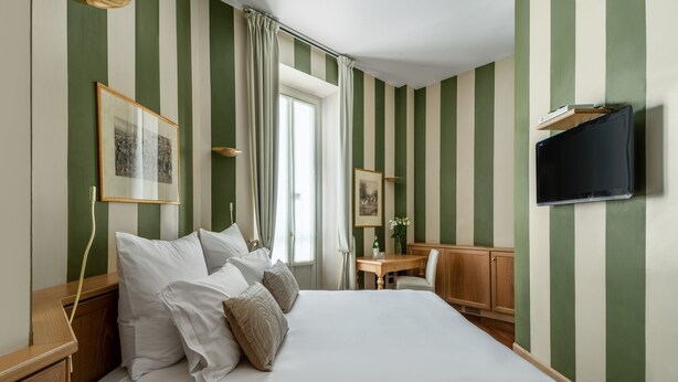 A hotel room with a large bed, a desk, and a TV mounted on the wall. - Numa Milan Camperio (Milan)