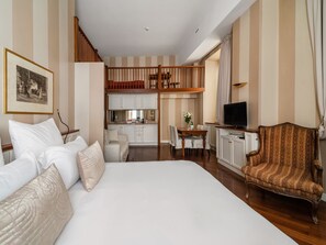 A hotel room with a large bed, a dining table with chairs, a TV, and a kitchen area. - Numa Milan Camperio (Milan)