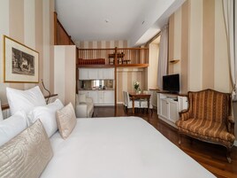 Una camera d'albergo con un letto grande, un tavolo da pranzo con sedie, una TV e un angolo cottura.