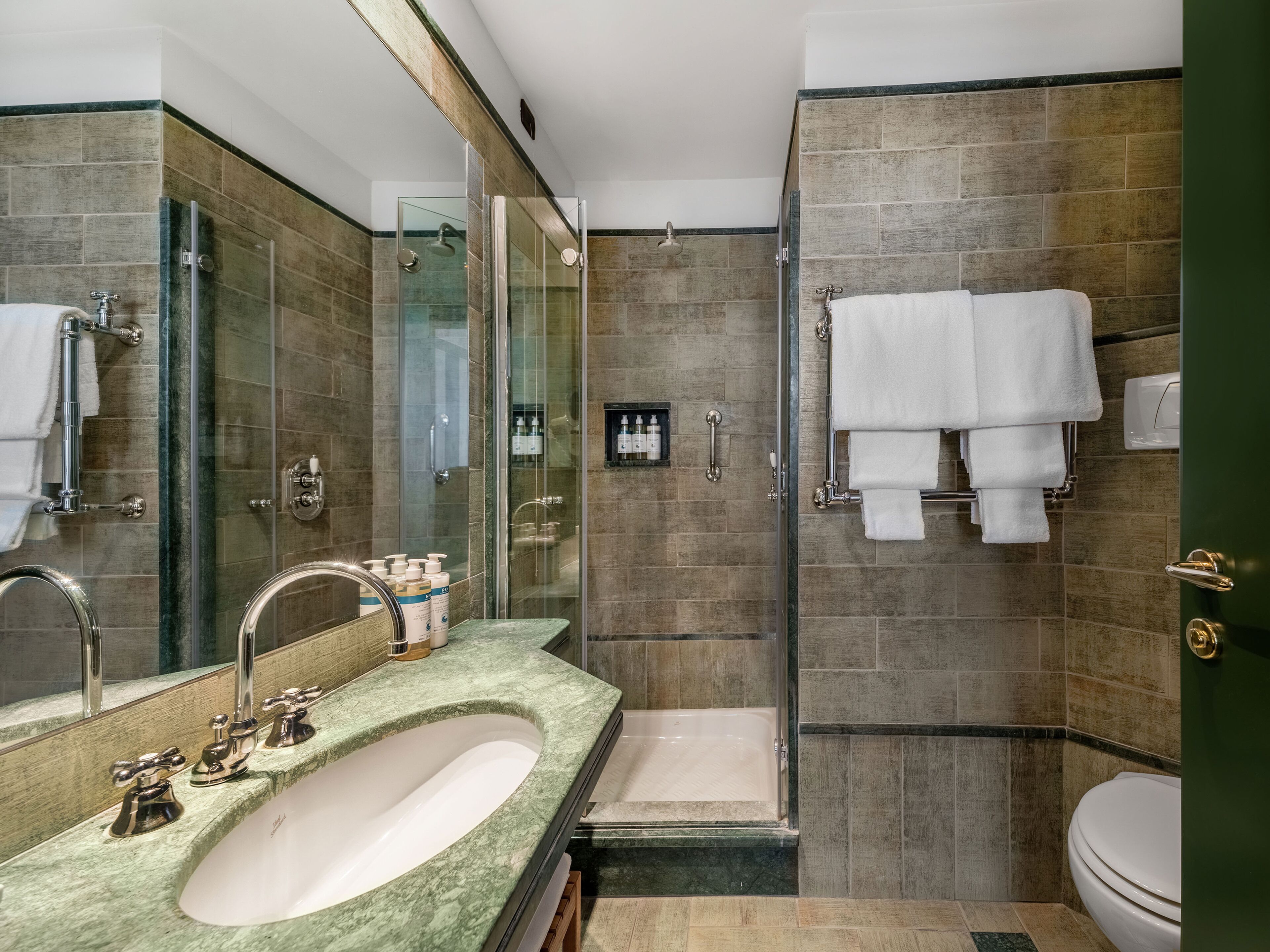 A modern bathroom with a large sink, a glass-enclosed shower, and a toilet.