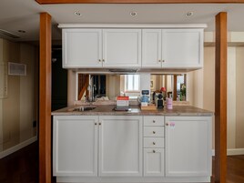 Een moderne keuken met witte kastjes, een granieten werkblad en een inbouwoven.