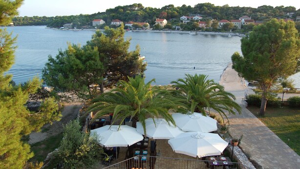 A waterfront restaurant with outdoor seating, overlooking a lake with houses in the background.