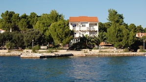 A two-story building with a red roof, located near a body of water.