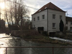 A white building with a red roof, a small bridge, and a river. - Auberge du Moulin d'Audenfort Guest House (Clerques)