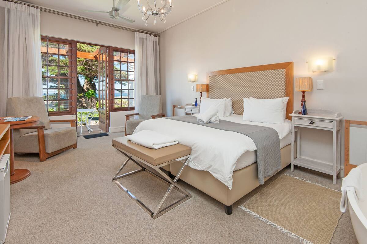 Una habitación de hotel con cama, mesitas de noche, una silla y un escritorio.