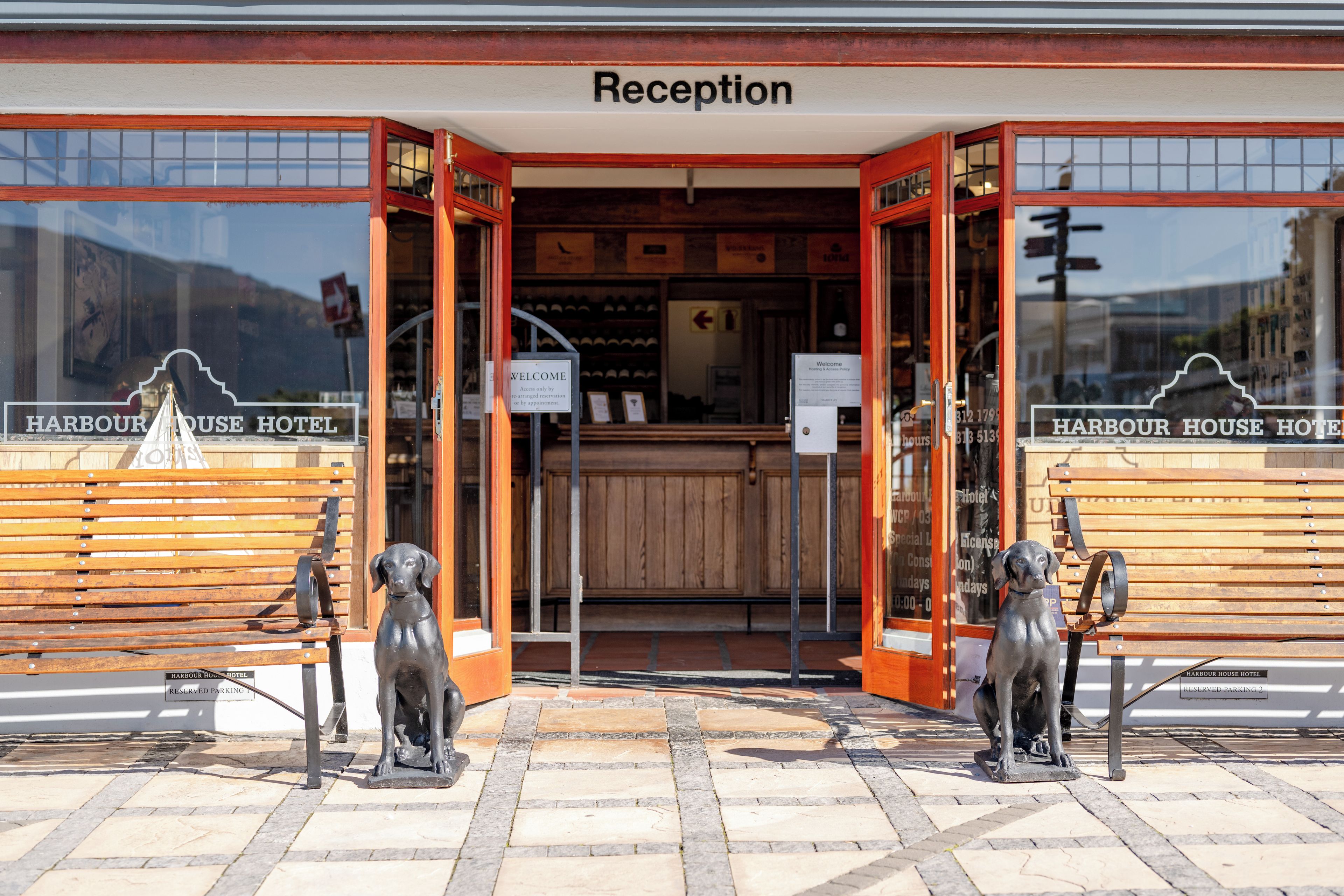 Una recepción de hotel con un banco de madera y dos estatuas de perros al frente.