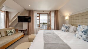 Ein Hotelzimmer mit Bett, einer Couch, einem Fernseher und einem Balkon mit Tisch und Stühlen.