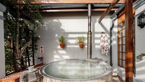Ein Whirlpool in einem überdachten Außenbereich mit Holzboden, Topfpflanzen und einem Feuerlöscher.