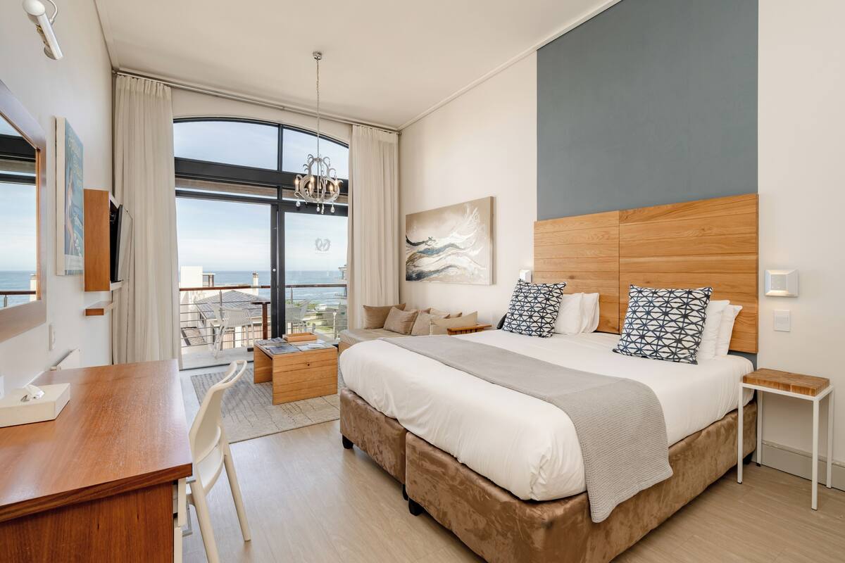 Una habitación de hotel moderna con una cama grande, un escritorio y un balcón con vistas.