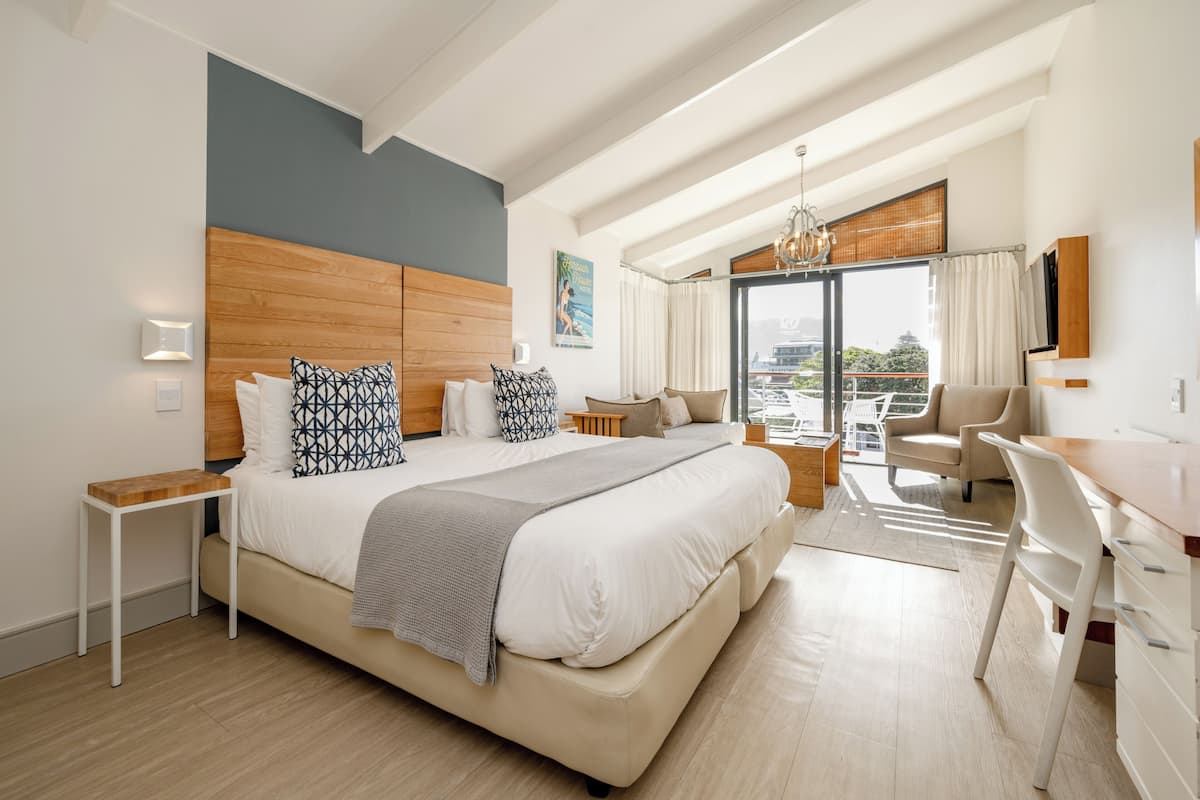 Habitación de hotel moderna con una cama grande, un escritorio, una silla y vistas a la ciudad.