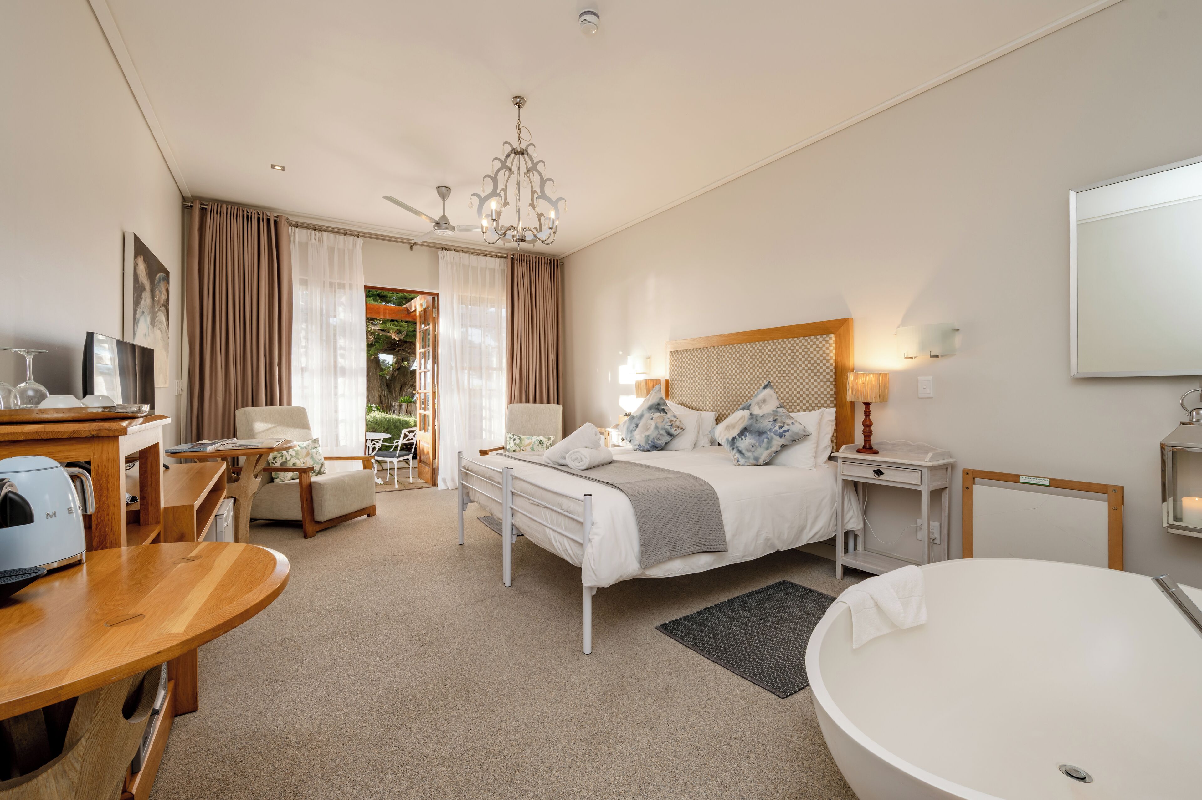 Een hotelkamer met een bed, een bureau, een stoel, een rond ligbad en een plafondventilator.
