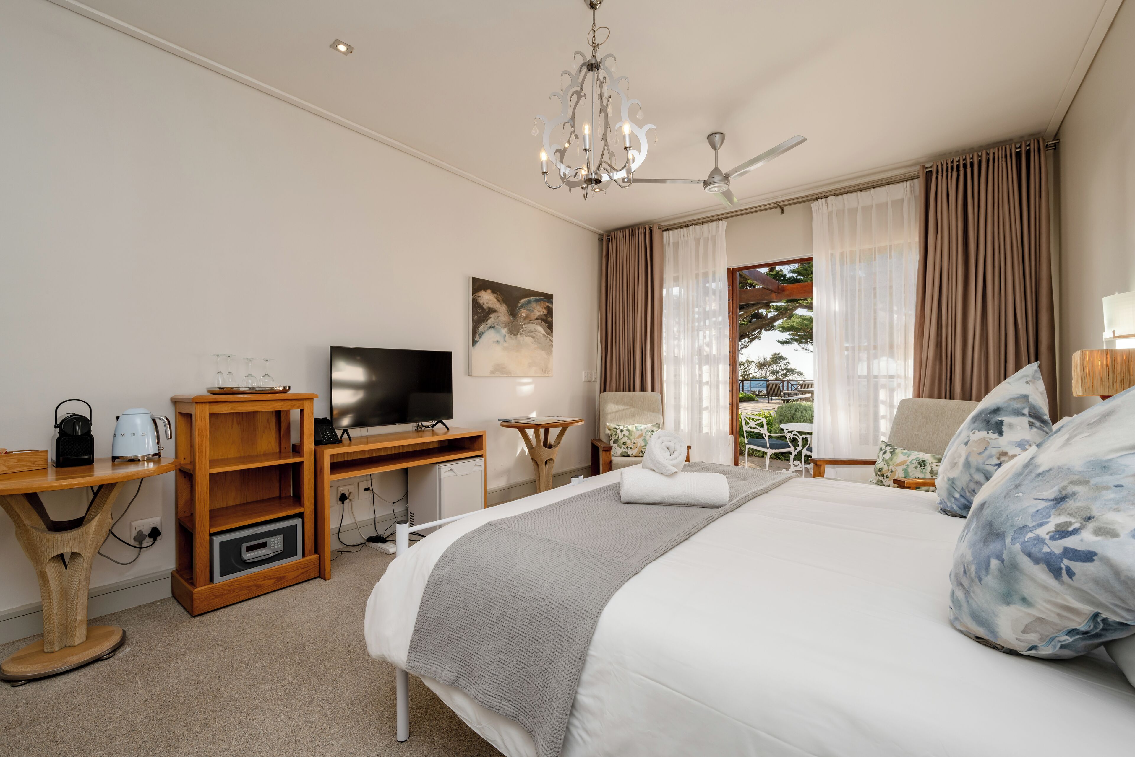 Habitación de hotel con cama, televisor, escritorio de madera y vistas al exterior.