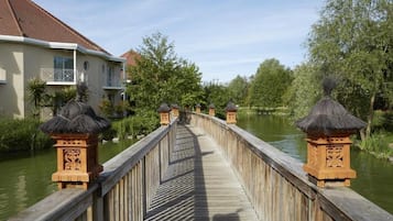 Een houten brug met decoratieve lantaarns, die naar een gebouw met een balkon leidt.