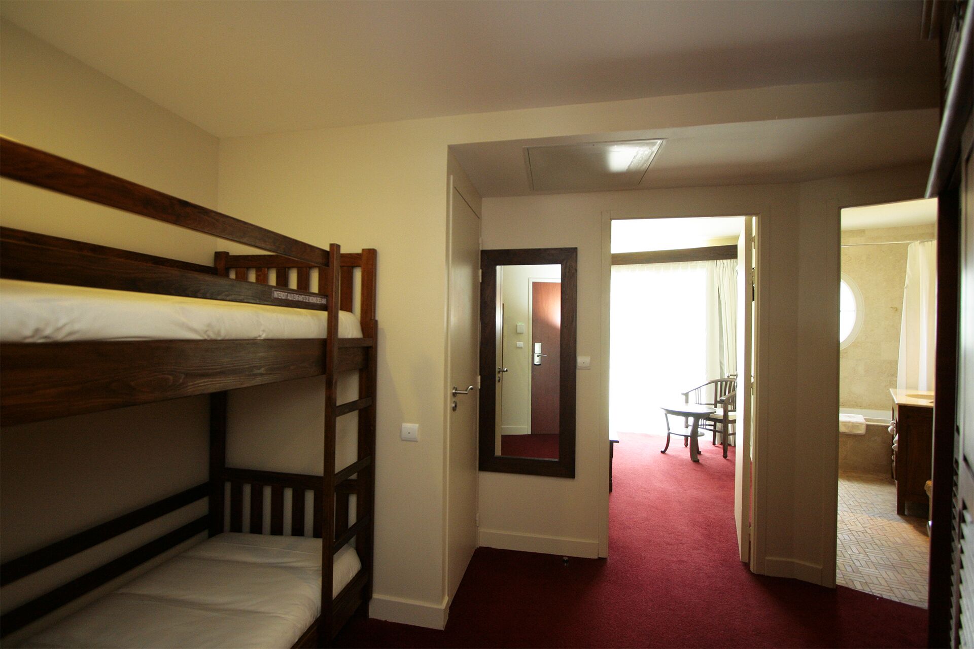 A room with two bunk beds, a door leading to a bathroom, and a small table with chairs.