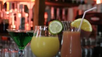Three cocktails on a bar counter with a blurred background of shelves stocked with bottles.