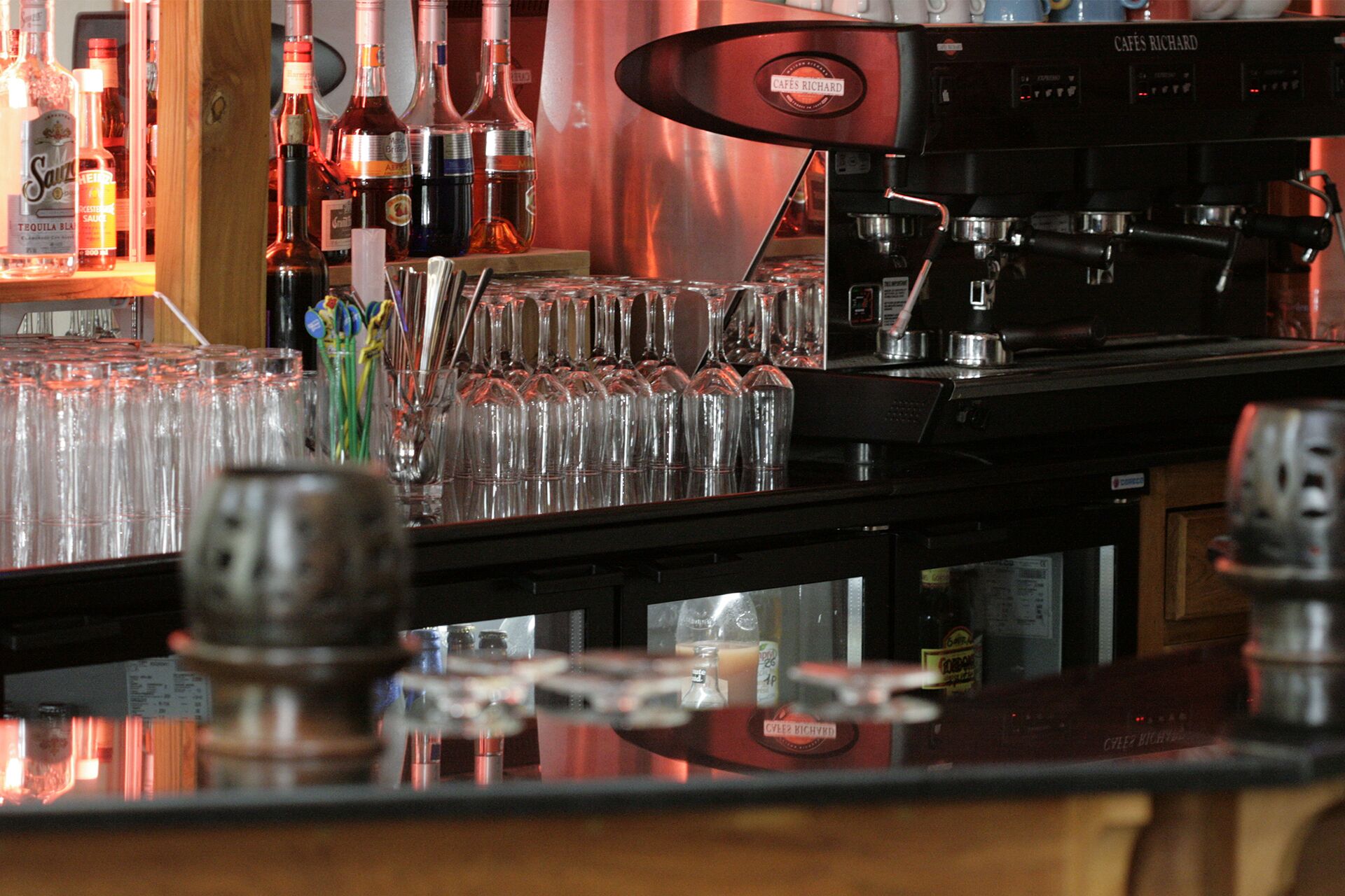 A bar area with a coffee machine, glasses, and bottles.