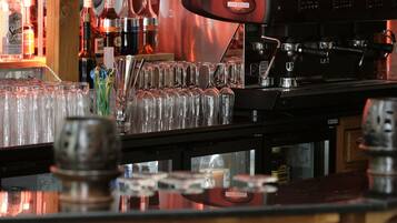 A bar area with a coffee machine, glasses, and bottles.