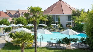 Un hotel con piscina rodeada de sombrillas y sillas de descanso.