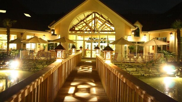 Un hotel con un atrio central, un paseo de madera y una zona de piscina.