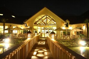 Un hotel con un atrio central, un paseo de madera y una zona de piscina.
