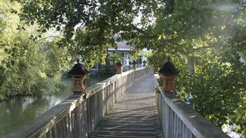Un ponte di legno con lanterne che conduce a un edificio con un tetto tradizionale.