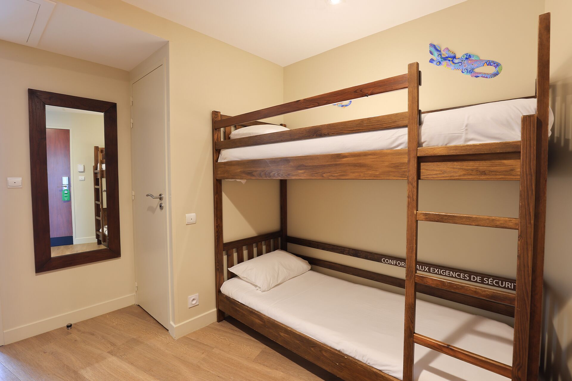 A bunk bed with a wooden frame, a white mattress, and a headboard with a decorative design.