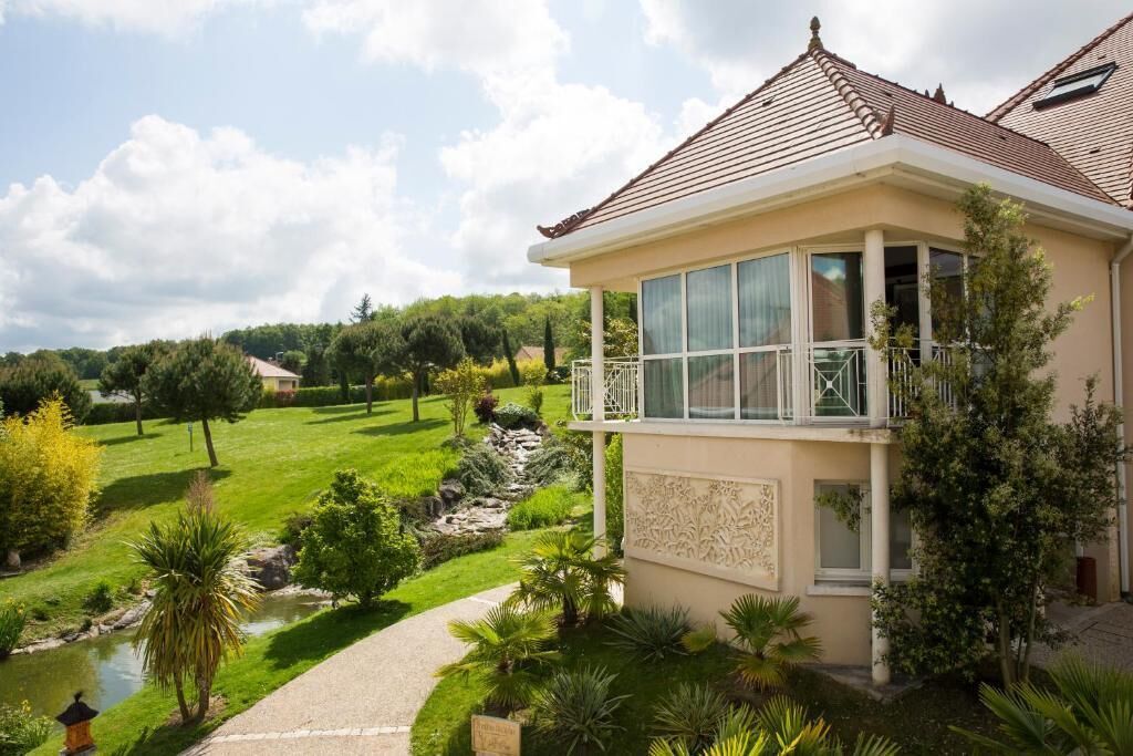 Ein Haus mit Balkon, Teich und gepflegtem Garten.