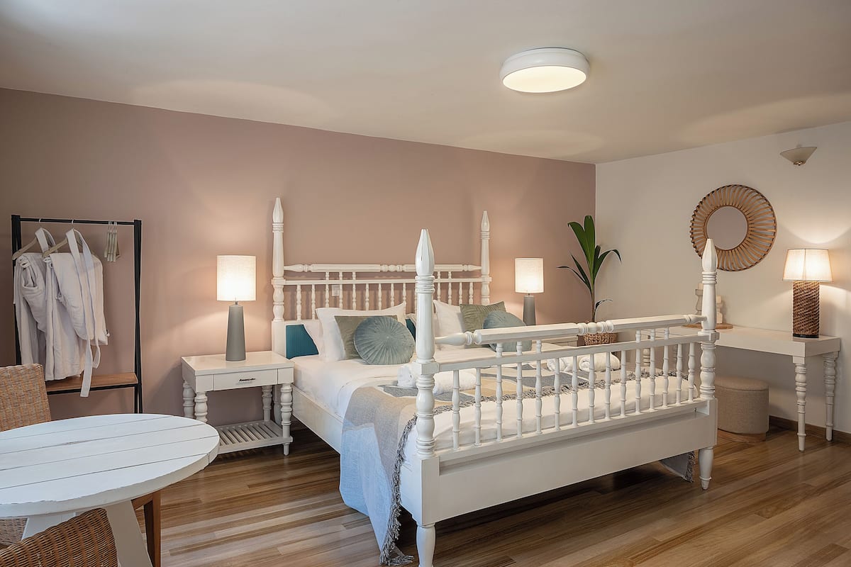 A bedroom with a four-poster bed, bedside tables, a round mirror, and a small table with chairs.