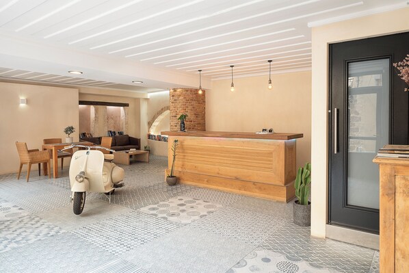 Un espace d’accueil avec un comptoir en bois, un scooter vintage et un escalier menant à un niveau supérieur.