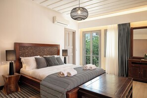 Un lit bien fait, recouvert d’une couvre-lit à motifs, une table de chevet et une lampe suspendue.