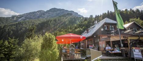 A mountain lodge with outdoor seating and a view of the mountains.