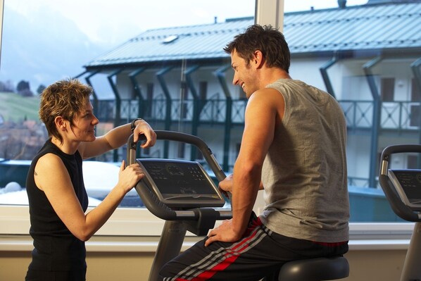 Un gimnasio con cinta de correr y vista a un edificio de techo metálico.