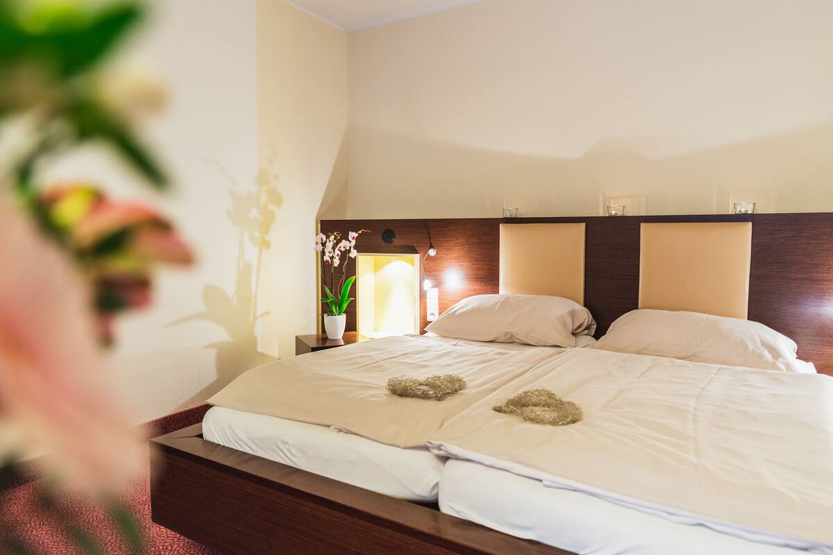 Una habitación de hotel con una cama grande, dos mesitas de noche y una planta en maceta.
