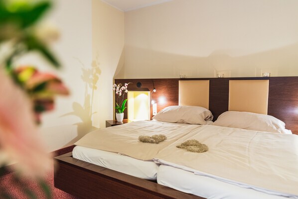 Una habitación de hotel con una cama grande, dos mesitas de noche y una planta en maceta.