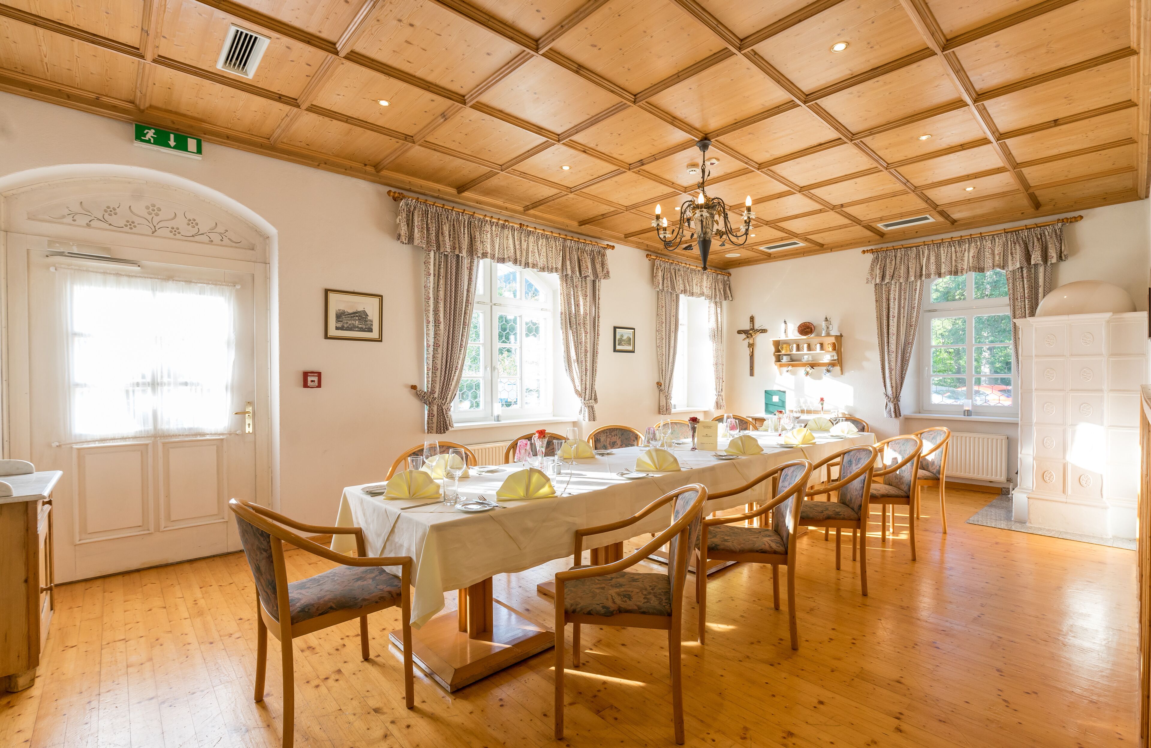 A dining room with a long table set for a meal, wooden chairs, and a chandelier.